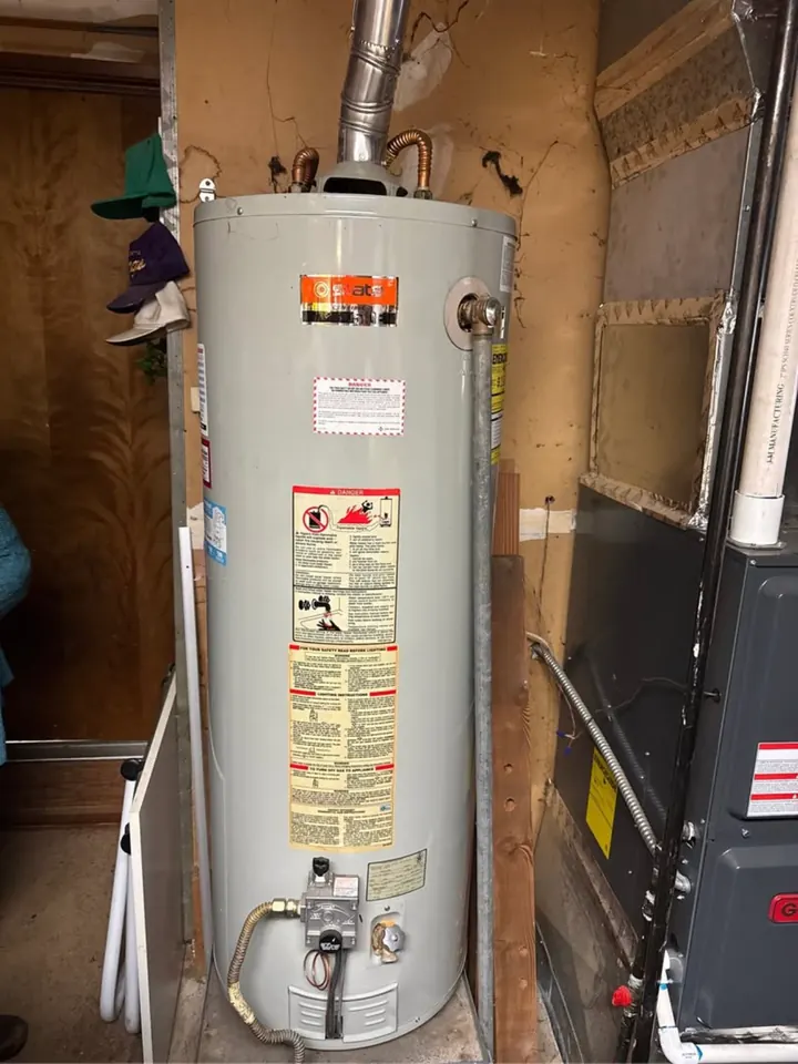 Older gas tank water heater in a utility closet next to a furnace